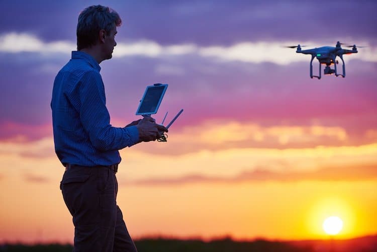 homme actionnant un drone au coucher du soleil